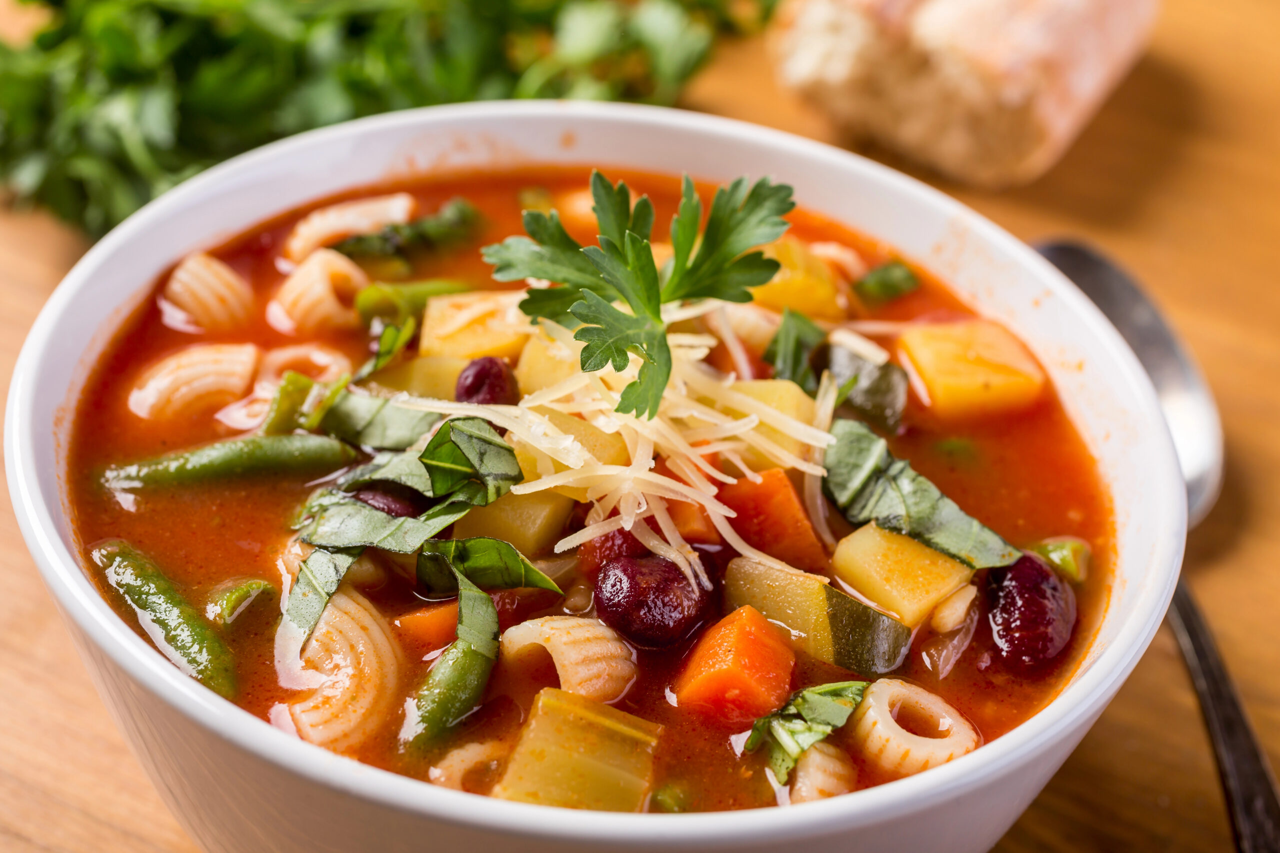 Bowl of tomato minestrone soup with zucchini, green beans, carrots, kidney beans and pasta