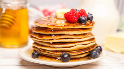 Stack of pancakes made with homemade baking mix, topped with butter, syrup, raspberries and blueberries.