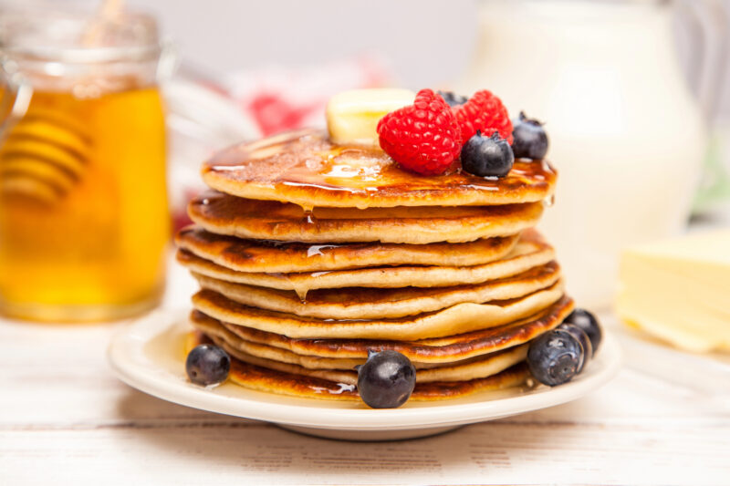 Stack of pancakes made with homemade baking mix, topped with butter, syrup, raspberries and blueberries.